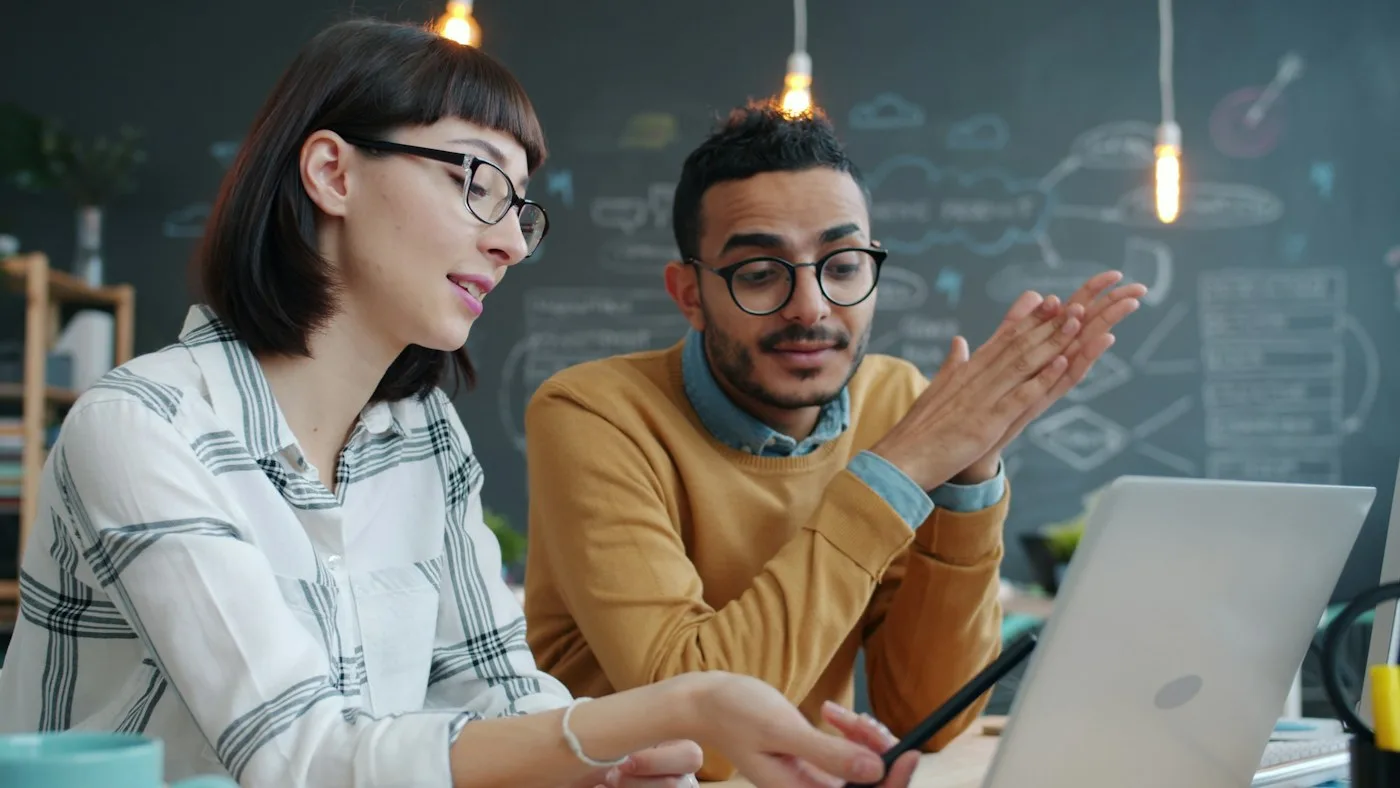 Two colleagues discussing a digital project at a laptop