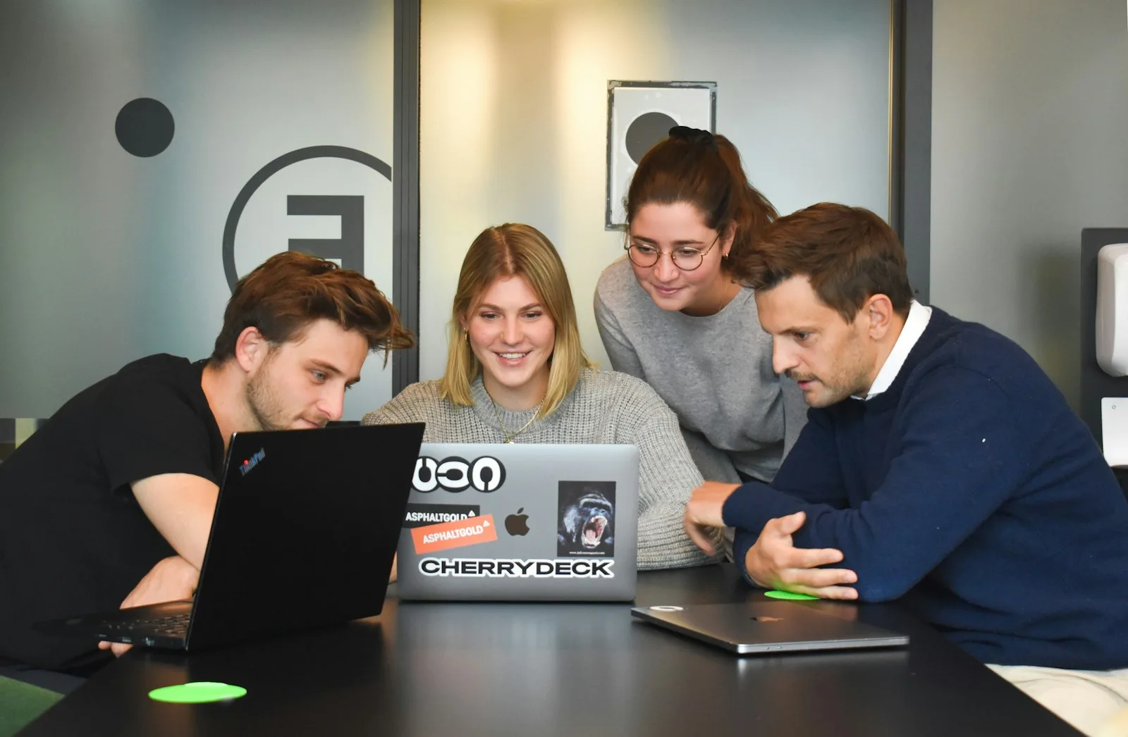 Four people collaborating around laptops in a workspace