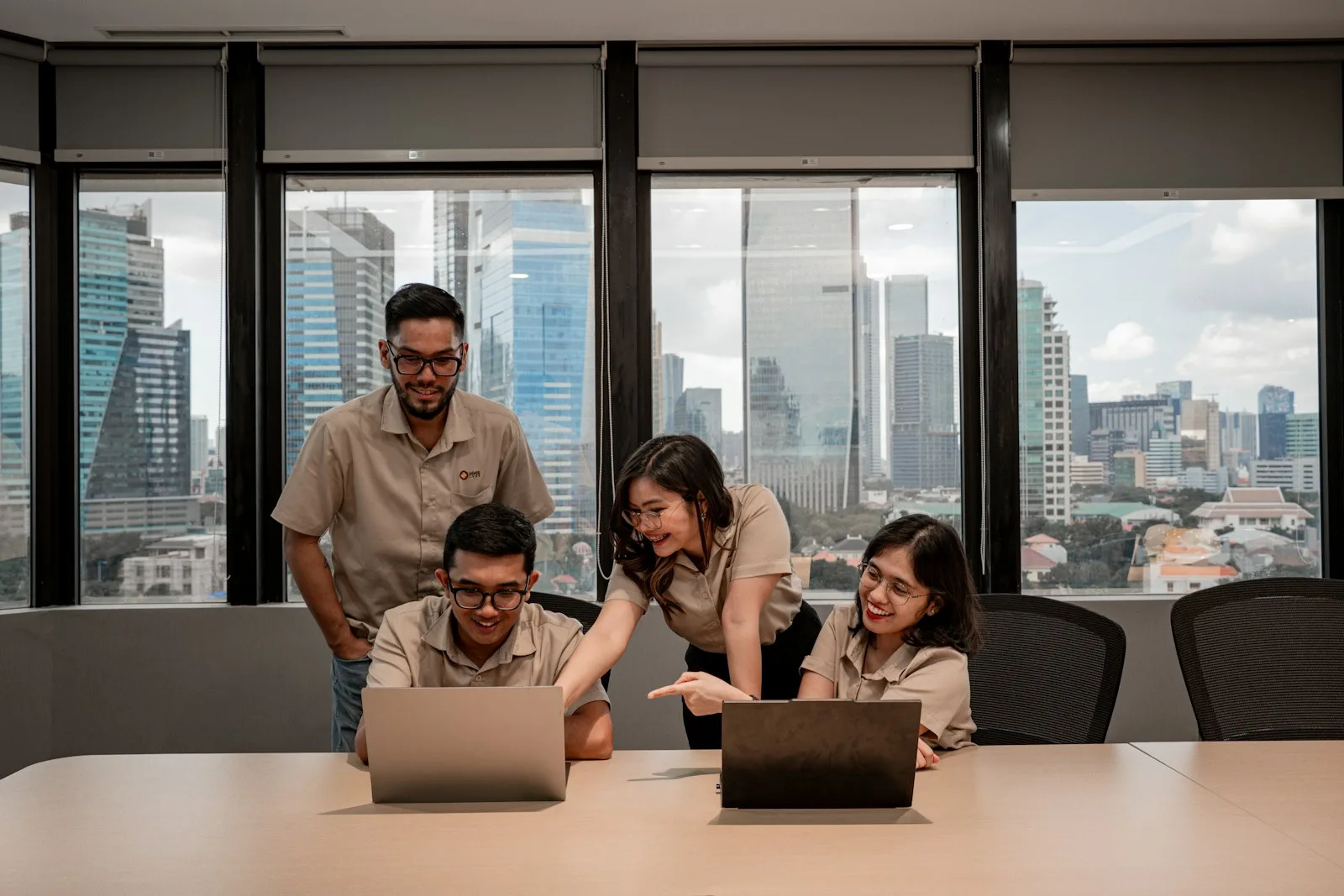 Four colleagues collaborating around laptops in an office